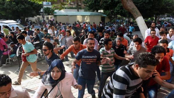 Egyptian protesters run for cover from tear gas fired by riot police during a demonstration in Cairo on April 25, 2016, against the handing over of two Red Sea islands to Saudi Arabia. (AFP/Mohamed el-Shahed)