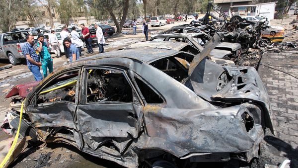 Iraqis stand at the site of an explosion at the parking across the street from the al-Yarmuk hospital in the west of Baghdad on April 14, 2015. (AFP/Ali al-Saadi)