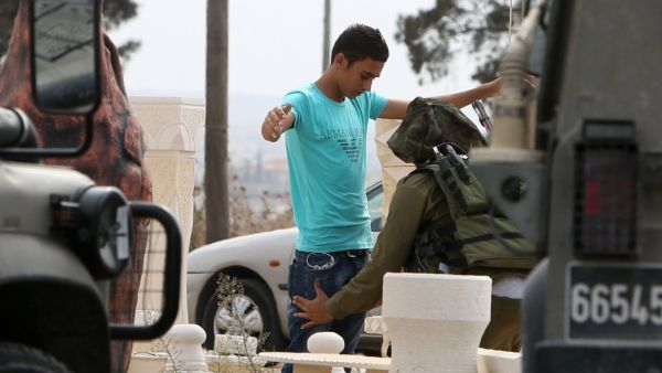 An Israeli soldier checks a Palestinian youth near the Jalama checkpoint, where a Palestinian man allegedly carried out a stabbing attack earlier. (AFP/File)