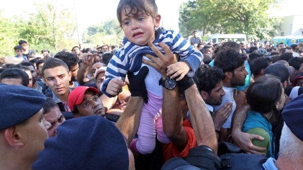 A man passes a child over to a police officer as they direct migrants and refugees onto buses at the train station in the city of Tovarnik, close to the Croatian-Serbian border, on September 17, 2015. (AFP/File) A man passes a child over to a police officer as they direct migrants and refugees onto buses at the train station in the city of Tovarnik, close to the Croatian-Serbian border, on September 17, 2015. (AFP/File)