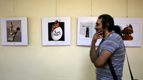 An Iranian man looks at cartoons displayed during an exhibition as part of the Daesh International Cartoon and Caricature Contest on May 31, 2015 at the Arasbaran gallery in Tehran. The exhibition displays the work of international cartoonists focusing on the crimes committed by Daesh in Syria and Iraq. (AFP/Atta Kenare)