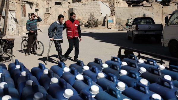 A member of the Qatari Red Crescent delivers aid, in the form of diesel fuel, to families in need in the rebel-held town of Beit Sawa, on the outskirts of the capital Damascus on March 7, 2016. (AFP/Amer al-Mohibany)