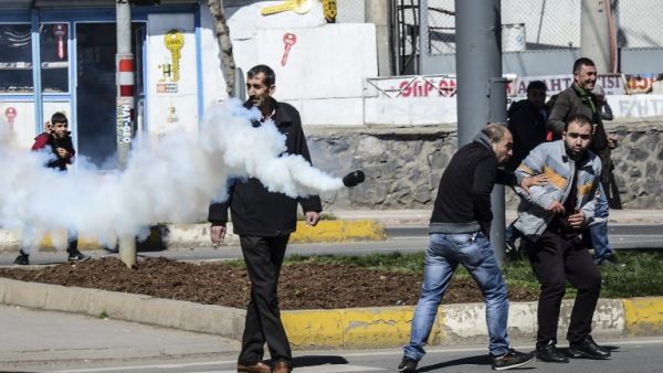 People react as a tear gas canister is thrown by Turkish police during clashes in central Diyarbakir on March 17, 2016. (AFP/Ilyas Akengin)