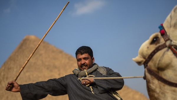 An Egyptian man rides a camel in front of one the Giza pyramids in the southern Cairo Giza distri. (AFP/file)