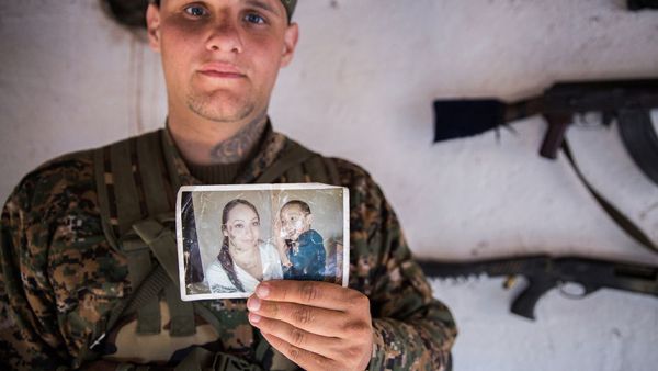 A 26-year-old from the US, nicknamed Hewal Dilsad by Kurdish fighters in northwestern Syria, displays a photograph of his wife and son.  (AFP/Uygar Onder Simsek)