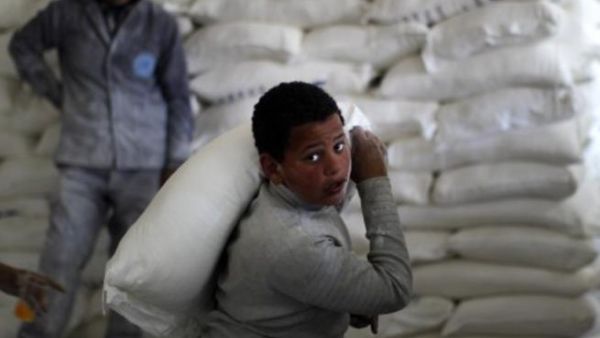 طفل فلسطيني يحمل كيس طحين في مركز توزيع اعانات الانروا/أ.ف.ب