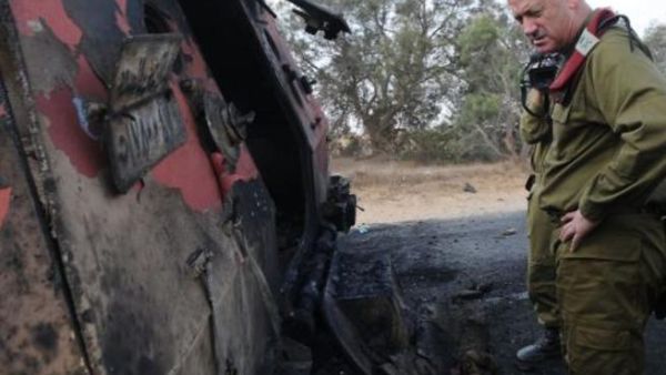 ضابط اسرائيلي يقف امام سيارة دمرها الطيران الاسرائيلي كان يستقلها عدد من منفذي الهجوم/أ.ف.ب