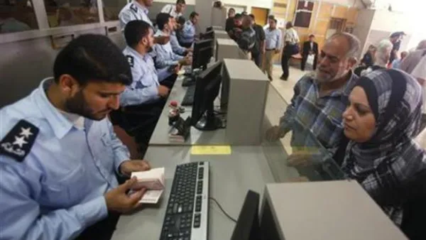 شرطي من حماس يفحص جواز سفر مسافر فلسطيني عند معبر رفح في جنوب قطاع غزة 
