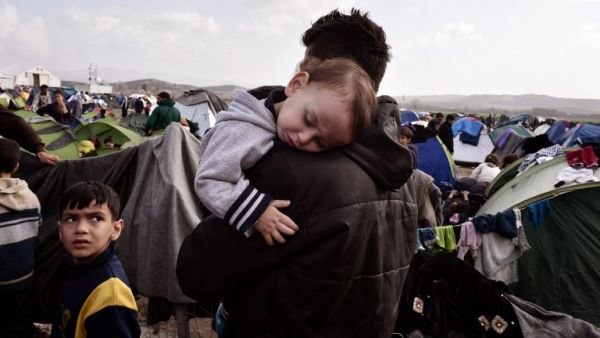 A baby sleeps in the arms of a man in the makeshift refugee and migrant camp at the Greek-Macedonian borders on March 1, 2016, where thousands are stranded due to travel restrictions on migrants. (AFP/Louisa Gouliamaki) A baby sleeps in the arms of a man in the makeshift refugee and migrant camp at the Greek-Macedonian borders on March 1, 2016, where thousands are stranded due to travel restrictions on migrants. (AFP/Louisa Gouliamaki)
