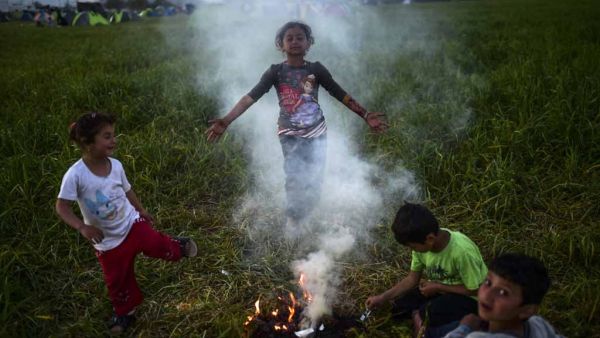 Refugee children play around a makeshift fire at a camp on the Greece-Macedonia border.  (AFP/Bulent Kilic)