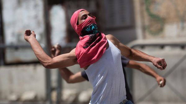 Palestinians throw stones towards Israeli forces during clashes in the West Bank town of Hebron. (AFP/File) Palestinians throw stones towards Israeli forces during clashes in the West Bank town of Hebron. (AFP/File)