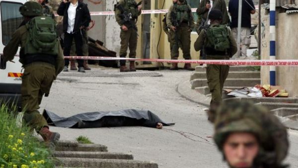 Israeli soldiers surround the body of one of the two Palestinians who were killed after attacking a soldier in Hebron, March 24, 2016. (AFP/File)