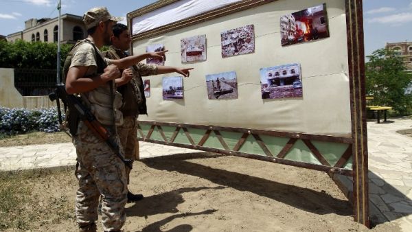 Shiite Houthi rebels look at photographs of destruction displayed in an exhibition condemning the Saudi-led military campaign on Sept. 17, 2015, in the Yemeni capital Sanaa. (AFP/Mohammed Huwais)