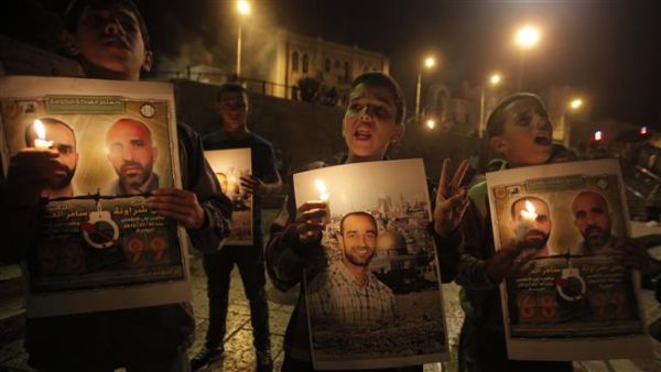Palestinians hold prisoners’ pictures and candles during a protest calling for the release of Palestinian inmates from Israeli jails and in support of prisoners on hunger strike in al-Quds (Jerusalem) on October 12, 2012. (AFP/File)