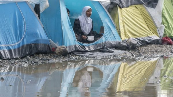 A refugee eats her dinner in a tent after a short rain at a makeshift camp for migrants and refugees at the Greek-Macedonian border near the village of Idomeni on April 24, 2016. (AFP/Joe Klamar)
