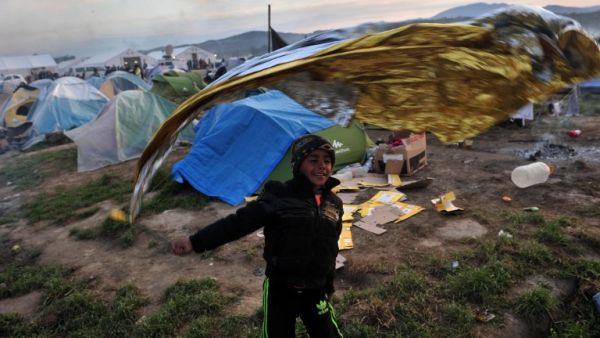A child plays with a survival blanket at the makeshift camp at the Greek-Macedonian border, near the Greek village of Idomeni on March 26, 2016, where thousands of refugees and migrants are stranded by the Balkan border. (AFP/Sakis Mitrolidis)