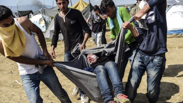 Migrants and refugees carry a man injured during clashes with Macedonian soldiers near their makeshift camp in the northern Greek border village of Idomeni, on April 10, 2016. (AFP/Bulent Kilic) Migrants and refugees carry a man injured during clashes with Macedonian soldiers near their makeshift camp in the northern Greek border village of Idomeni, on April 10, 2016. (AFP/Bulent Kilic)