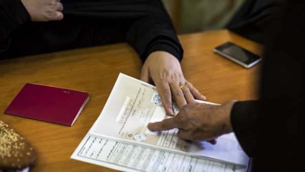An Iranian woman presses her inked-finger on a registering paper during the parliamentary and Assembly of Experts elections at a polling station at Massoumeh shrine in the holy city of Qom, south of the capital Tehran, on Feb. 26, 2016. (AFP/Behrouz Mehdi)