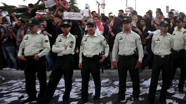 Iranian policemen stand guard as supporters of Iranian moderate presidential candidate, Hassan Rowhani, attend a street rally at Vanak square in northern Tehran on June 12 (Behrouz Mehri / AFP)