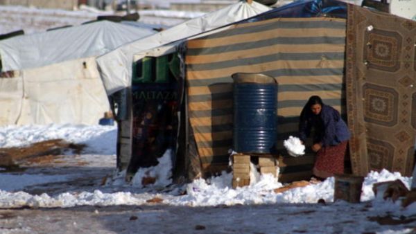 A Syrian woman shovels snow following a storm in the eastern Lebanese city of Baalbek on December 12, 2013. [AFP]