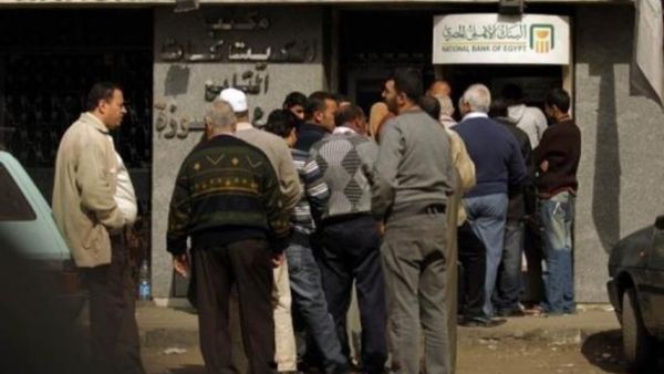 مواطنون يقفون امام آلة للصرف الالي في القاهرة
