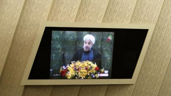 IRAN, Tehran : Iranian President Hassan Rowhani is seen on a TV screen as he speaks during a parliament session to elect the cabinet members on August 15, 2013. AFP PHOTO/BEHROUZ MEHRI
