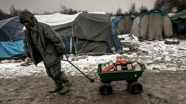 A man carries food at the refugee and migrant camp in Grande-Synthe near Dunkirk, northern France, where 2,500 refugees from Kurdistan, Iraq and Syria live. (AFP/File)