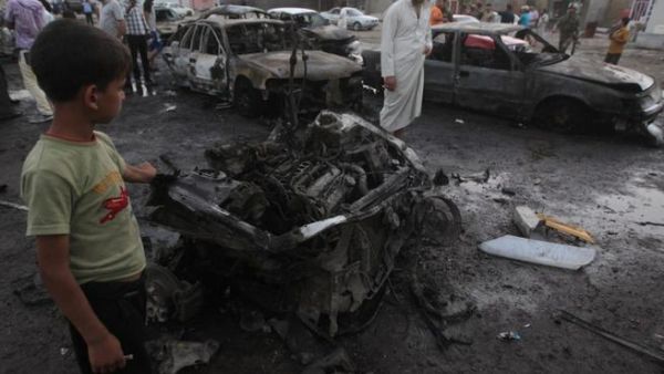 Iraqis gather at the scene of one of the two car bombs that exploded near an used car dealerships in Baghdad's Habibiyah area on May 27(Ahmad Al-Rubaye/ AFP)