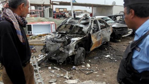 An Iraqi policeman and civilian inspect the wreckage of a car bomb in Baghdad on April 15 (AFP/ Ahmad Al Rubaye)