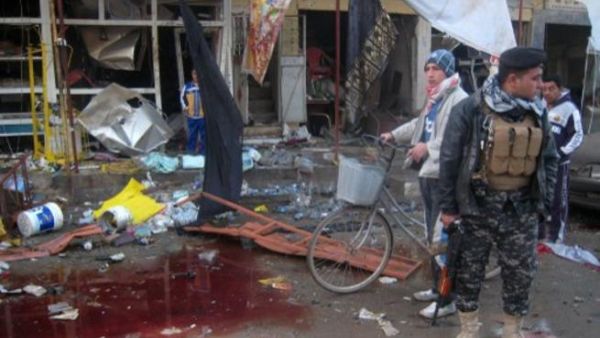 جندي عراقي يقف الى جانب بركة من دماء ضحايا تفجير في طوزخرماتو/أ.ف.ب