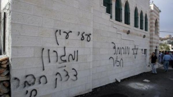 فلسطيني يتكلم على الهاتف في 5 ايلول/سبتمبر الى جانب كتابات بالعبرية على جدار مسجد في الضفة الغربية
