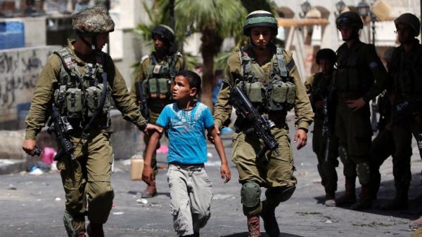 Israeli soldiers arrest a young Palestinian boy following clashes in the West Bank town of Hebron on June 20, 2014. (AFP/Thomas Coex)