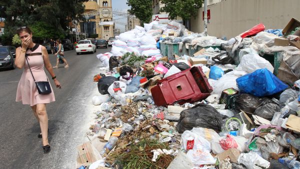 A woman holds her breath as she walks near a temporary garbage dump in the neighbourhood of Jdeideh, northeast of the Lebanese capital Beirut on September 1, 2016.
(ANWAR AMRO / AFP)