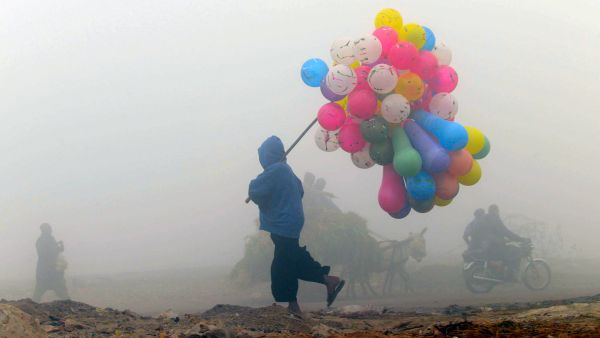 A balloon vendor walks through the fog in Lahore, Pakistan.  (AFP/Arif Ali)