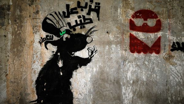 A rat beckons viewers to "come taste the goodies" above a pile of trash in Beirut, amidst Lebanon's garbage crisis.  (AFP/Joseph Eid)