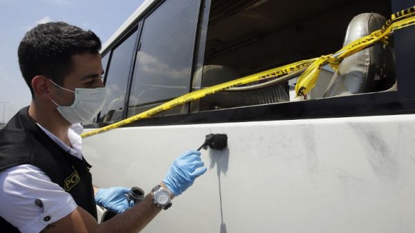 Lebanese policemen search for evidence at the site where at least twenty people were injured when masked assailants wielding knives attacked a bus in Beirut.(Joseph Eid / AFP)