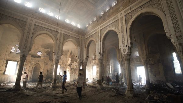 Residents walk through debris and rubble inside the burnt-down mosque of Rabaa al-Adawiya (AFP/KHALED DESOUKI)