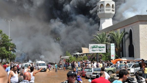 LEBANON, Tripoli : TOPSHOTS
Smoke is seen above people gathering outside a mosque on the site of a powerful explosion in the northern Lebanese city of Tripoli on August 23, 2013. AFP PHOTO IBRAHIM CHALHOUB