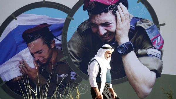 LEBANON, Aita Al-Shaab : Images of grieveing Israeli soldiers adorns a wall as a supporter of the Shiite Muslim Hezbollah movement walks past. AFP PHOTO / MAHMOUD ZAYYAT