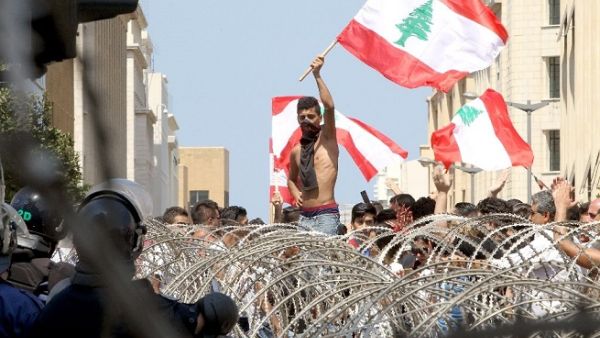 Lebanese protesters wave the national flag in front of a barbed wire fence as large crowds rally in Beirut on August 23, 2015. (Anwar Amro/ AFP)