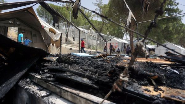 A man walks through the burned tents after a riot at a Lesbos detention center. (AFP/Stringer) A man walks through the burned tents after a riot at a Lesbos detention center. (AFP/Stringer)