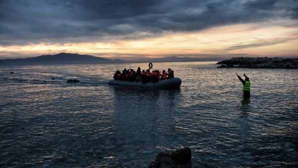 Refugees and migrants massed onto an inflatable boat reach Mytilene, northern island of Lesbos, after crossing the Aegean sea from Turkey on February 17, 2016. (AFP/Aris Messinis)