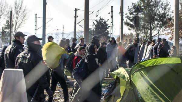 Greek policemen remove Afghan migrants from the Macedonian border to enable other migrants from Syria and Iraq to cross near Gevgelija on February 23, 2016. (AFP/Robert Atanasovski)