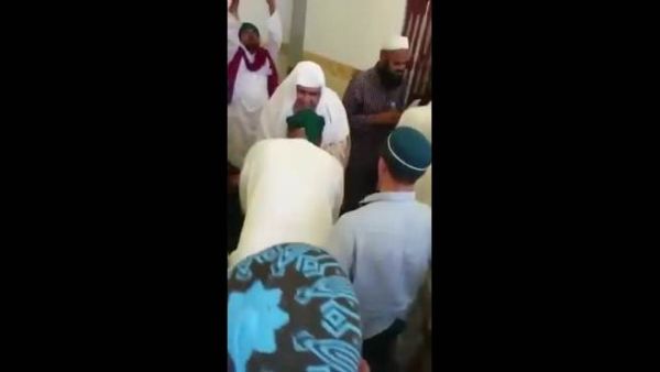 آسيوييون يقبلون يد امام مسجد بمكه ويتبركون بشرب الماء من بعده