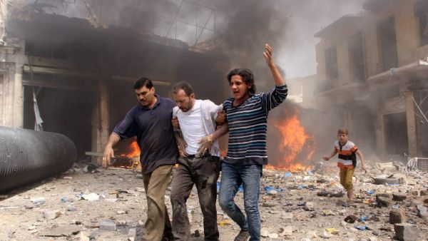 Syrian men help an injured person following a reported barrel bomb attack by Syrian government forces that hit an open market in the northern city of Aleppo, on June 3, 2015, killing and injuring people. (AFP/Karam al-Masri)