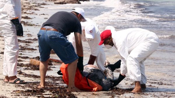 Members of the Libyan Red Crescent, wearing protective white clothing and masks, collect the body of a migrant that had washed ashore on a beach on Aug. 28, 2015 in the port town of Zuwara west of Tripoli. (AFP/Mahmud Turkia) Members of the Libyan Red Crescent, wearing protective white clothing and masks, collect the body of a migrant that had washed ashore on a beach on Aug. 28, 2015 in the port town of Zuwara west of Tripoli. (AFP/Mahmud Turkia)