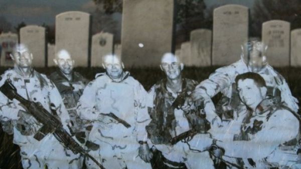 Headstones are reflected in a photograph that is leaning against the headstone for Iraq war casualty U.S. Army Master Sgt. Tulsa Tulaga Tuliau on the 10th anniversary of the beginning of the war in Iraq. (Getty Images/AFP)