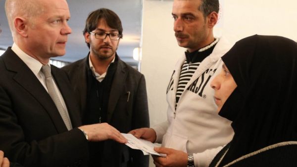 British Foreign Secretary of State for Foreign Affairs William Hague (L) talks with Syrian refugees (R and 2ndR) at a World Food Programme Center in Burj Hammoud's area on the northern outskirts of Beirut. (AFP PHOTO POOL MOMAMED AZAKIR)