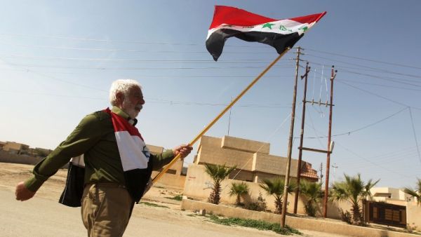 A man holds the Saddam-era national Iraqi flag as he walks in Tikrit. (AFP PHOTO/AHMAD AL-RUBAYE)
