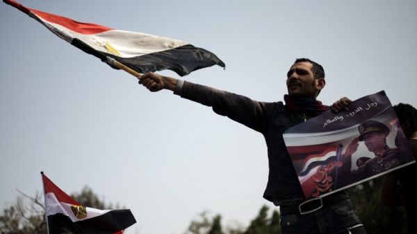 An Egyptian protestor waves his national flag while holding a poster of slain former Egyptian president Anwar Sadat with a slogan reading in Arabic "Man of war and peace" during a demonstration in support of the Egyptian army and against the Muslim Brotherhood. (AFP PHOTO/GIANLUIGI GUERCIA) An Egyptian protestor waves his national flag while holding a poster of slain former Egyptian president Anwar Sadat with a slogan reading in Arabic "Man of war and peace" during a demonstration in support of the Egyptian army and against the Muslim Brotherhood. (AFP PHOTO/GIANLUIGI GUERCIA)